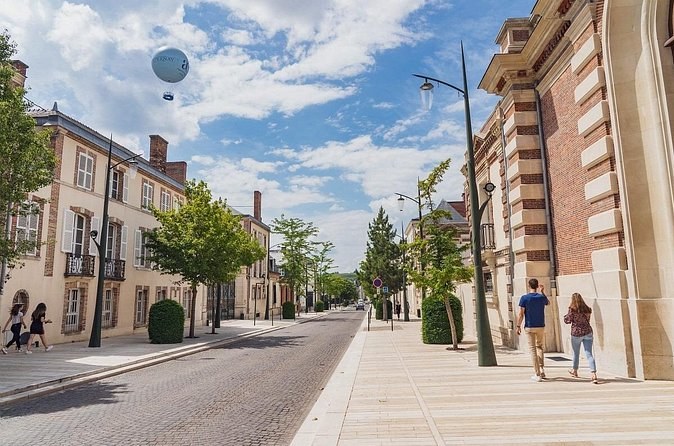 A wide avenue of brick and stone house fronts, a tethered balloon in the sky above