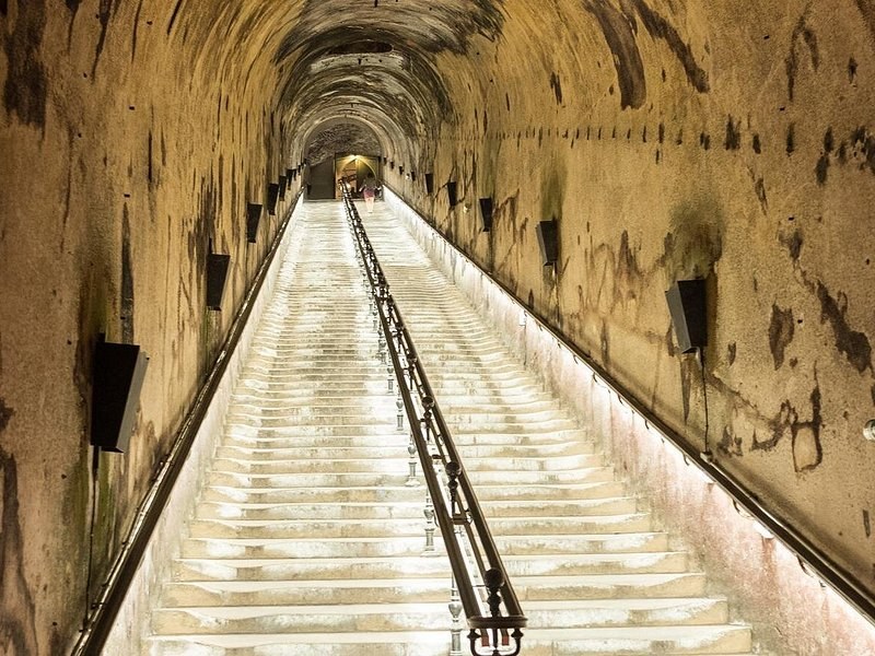 A long stairway lit in white, running down between chalk walls into the cellars