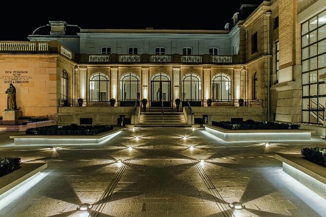 The Moët & Chandon courtyard in Épernay lit at night, the Dom Pérignon statue beside the house plaque