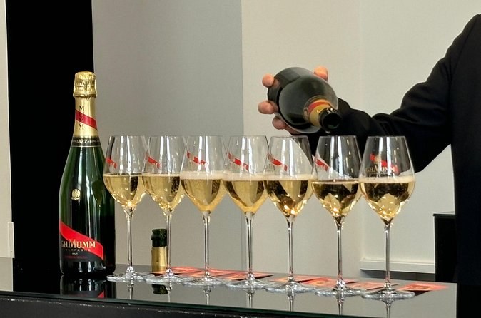 A bottle pouring into a row of flutes at a tasting bar