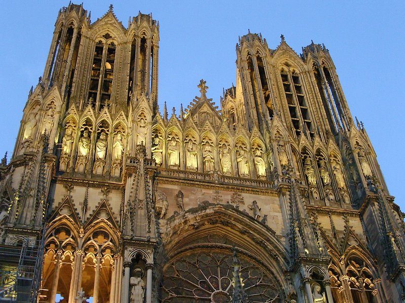 The statues and gables of Reims Cathedral's west front lit gold at dusk