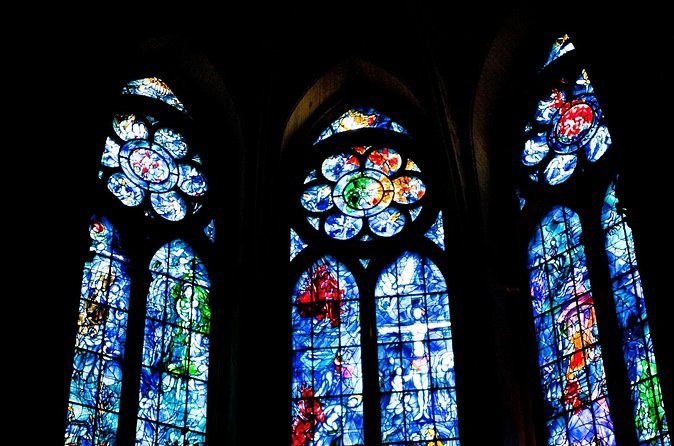 Three tall stained-glass windows in deep blue and red, lit from outside