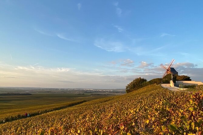 A windmill on a rise above vines turning gold and red in autumn